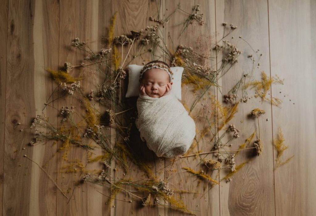Wrapped Newborn on Wood Floor with Florals
